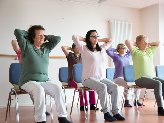 A group of people sit in chairs stretching